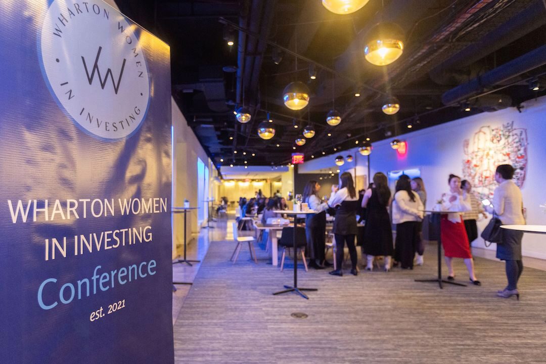 The Wharton Women in Investing conference banner with participants in the background.