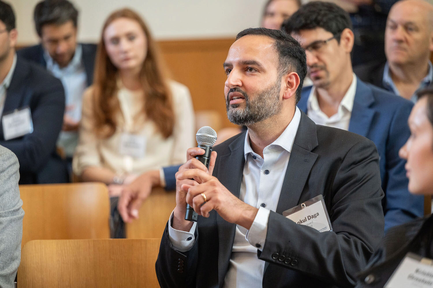 A person speaking into a microphone with other people in the background