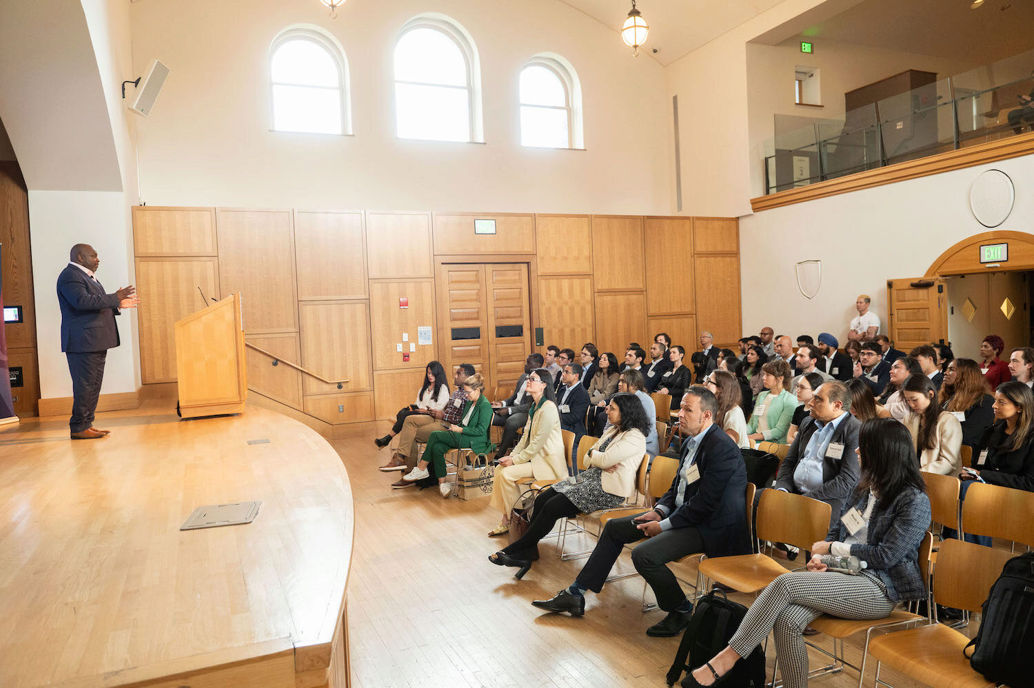 An audience watches a presenter onstage
