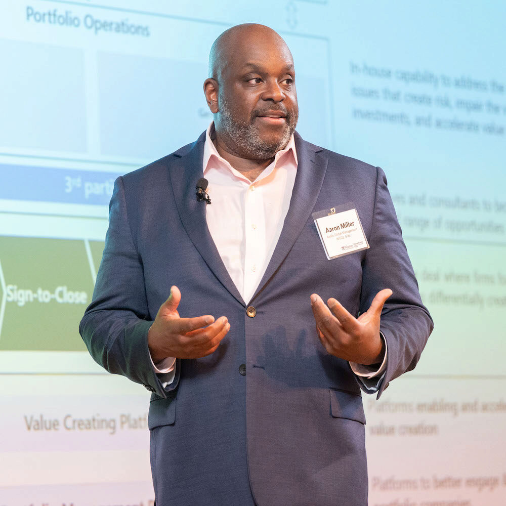 A speaker motions with his hands while giving a presentation