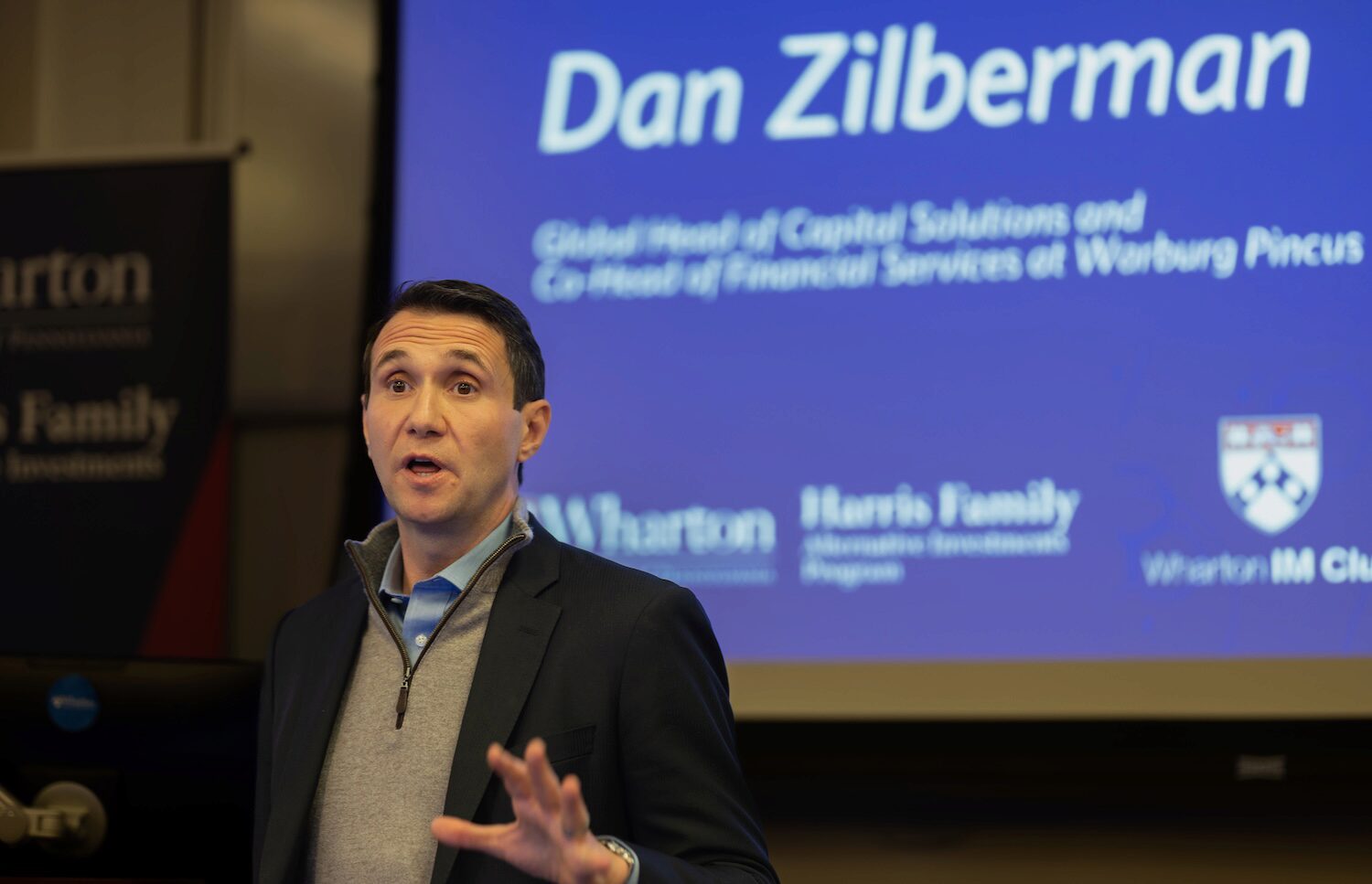 A speaker gestures with his hand while giving a presentation.